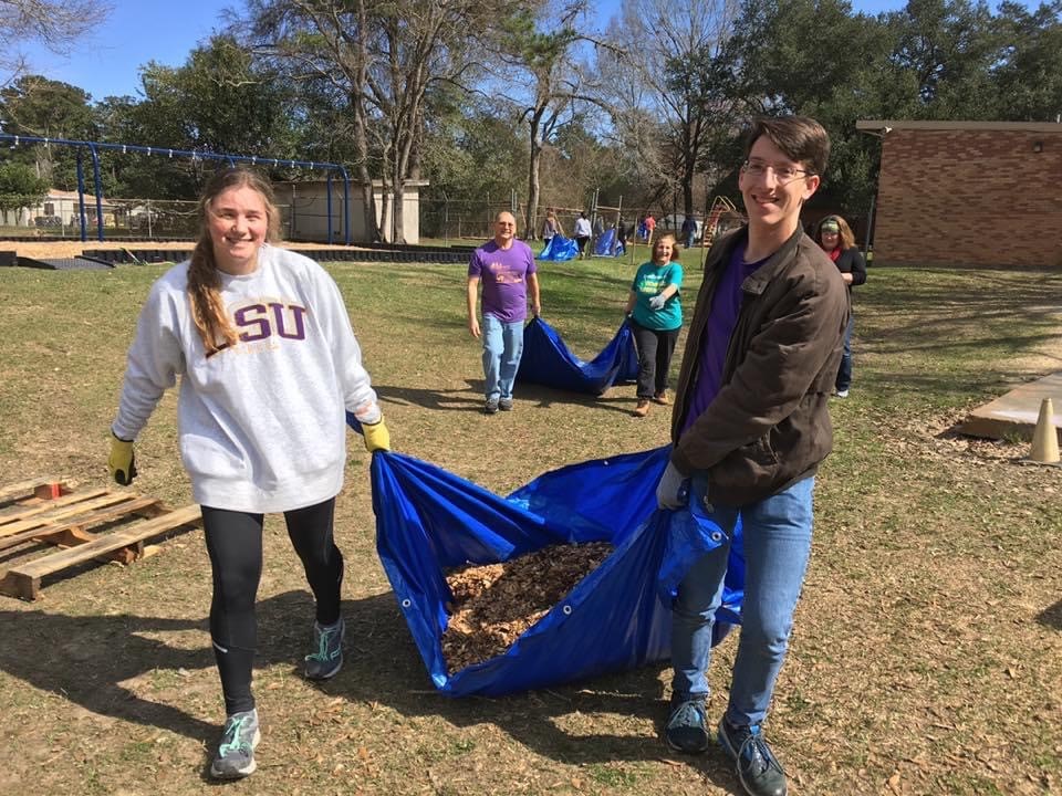 female and male student hold blue trash bag together