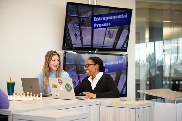 Two students behind laptop in lab space.