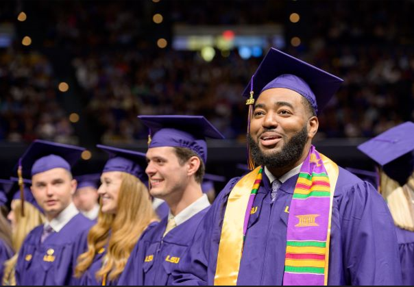 Group of students in cap and gowns smiling at graduation.