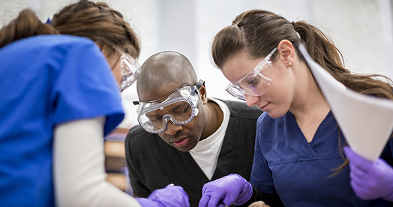 Photo of three students in the cadaver lab.