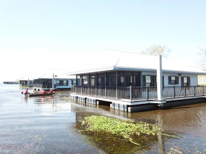 House with water coming up to the foundation and a boat floating near it